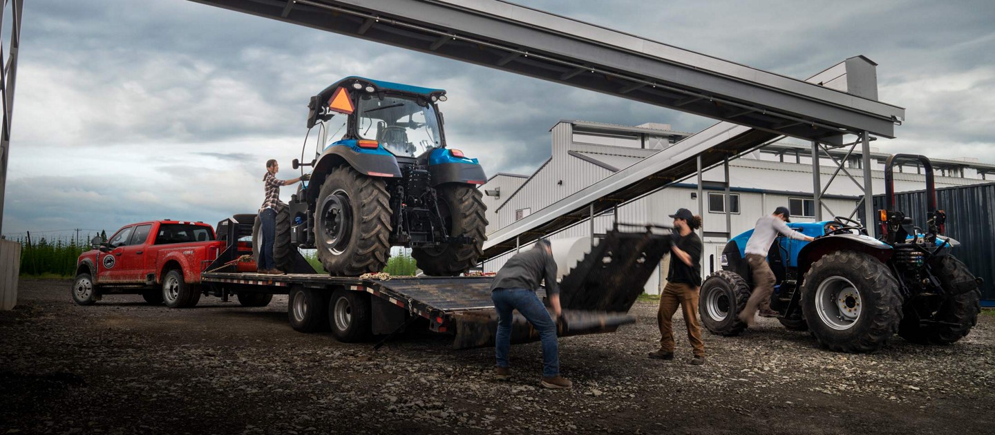People loading a large tractor onto a trailer hitched to a 2025 Ford Super Duty® F-450® XL pickup