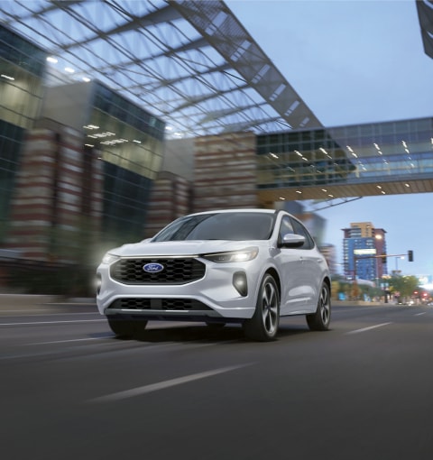 2020 Ford Edge S T in Ford Performance Blue being driven around curve on road near hills with large city in background