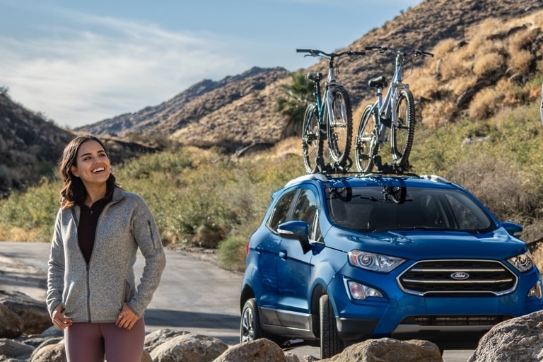 Man and woman standing on rocks with 2021 Ford Escape parked on the road nearby