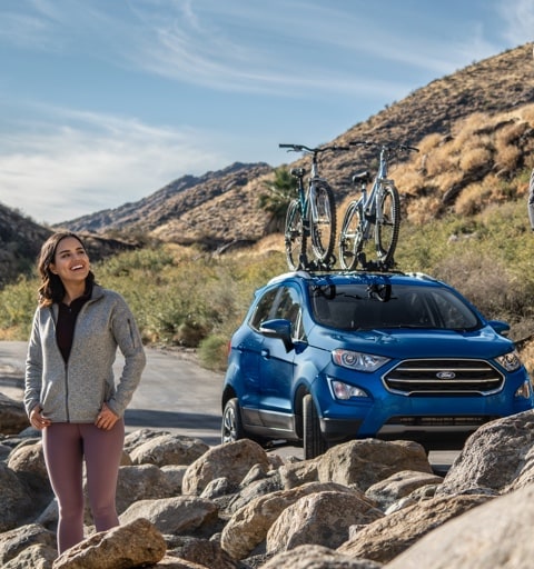 Man and woman standing on rocks with 2021 Ford Escape parked on the road nearby