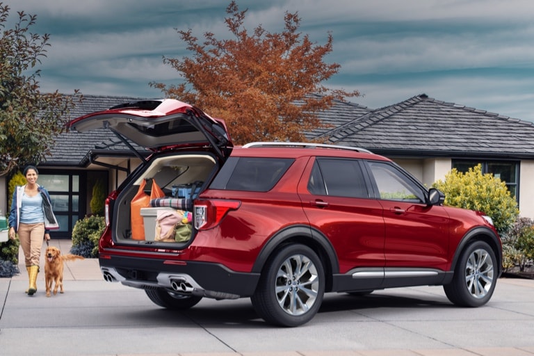 Man woman and dog near 2021 Ford Expedition in Rapid Red with open liftgate showing a trunk full of groceries