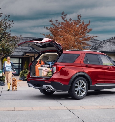 Man woman and dog near 2021 Ford Expedition in Rapid Red with open liftgate showing a trunk full of groceries