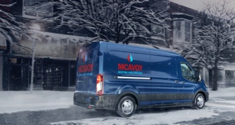 Blue 2020 Ford Transit Cargo Van with custom branding being driven on snowy street during storm. 