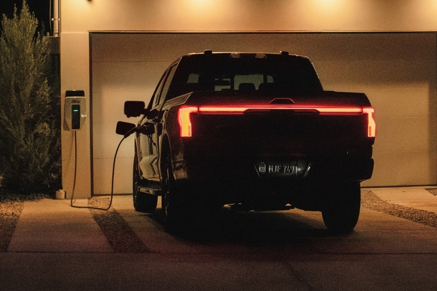 F-150 Lightning parked in a residential driveway and plugged into a home charging station.