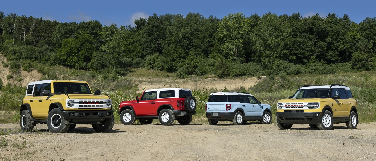 Two 2023 Bronco® and two Bronco® Sport models parked in a clearing. One Heritage and one Heritage Limited per model.