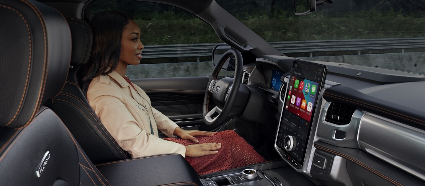 Interior view of a woman driving a vehicle hands-free on a highway.