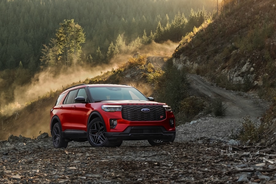 A Ford Explorer is parked alongside a dirt road in a hilly, scenic area.