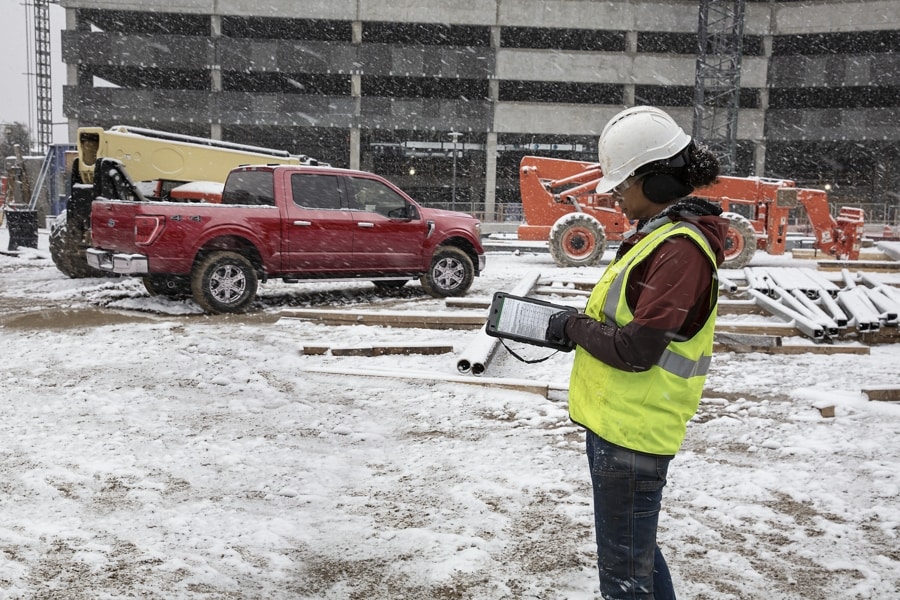 Female contractor at a snow-covered worksite with a 2022 Ford F-150® in Rapid Red in the background