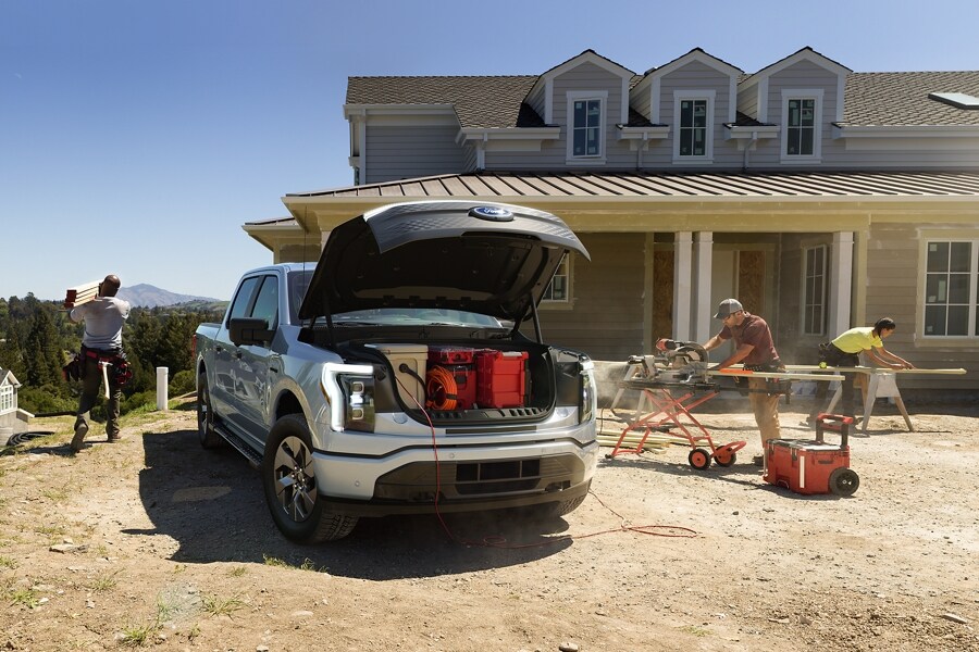 A 2022 Ford F-150® Lightning™ with the front trunk open parked on a job site