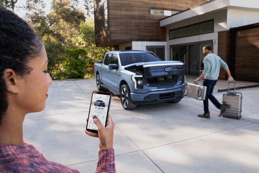 Close-up of a woman using the FordPass™ App to open the front trunk of the Ford F-150® Lightning™