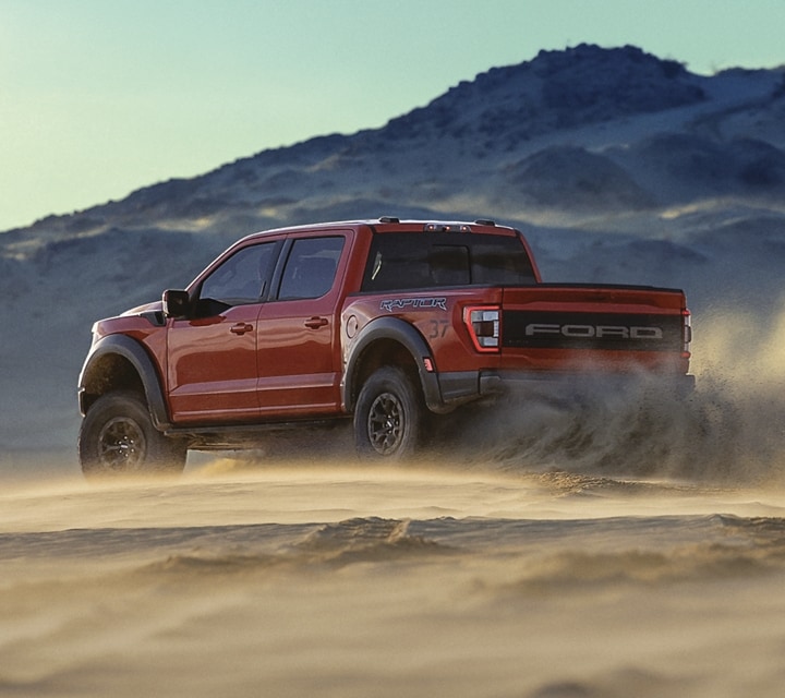 2023 Ford Raptor® in Rapid Red kicking up sand on a dune