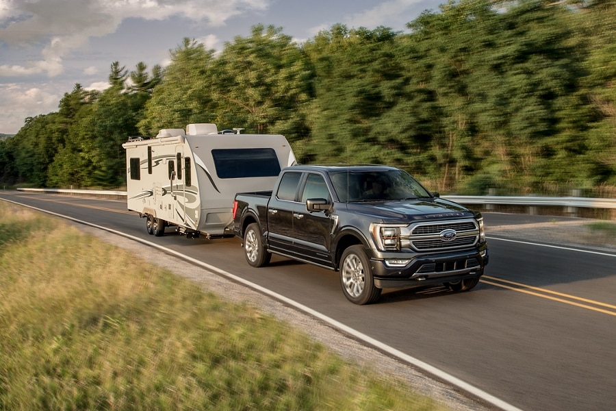A Ford F-150 pulls a camper along a highway.