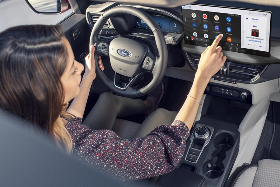 A woman interacts with a touchscreen while driving a Ford vehicle.