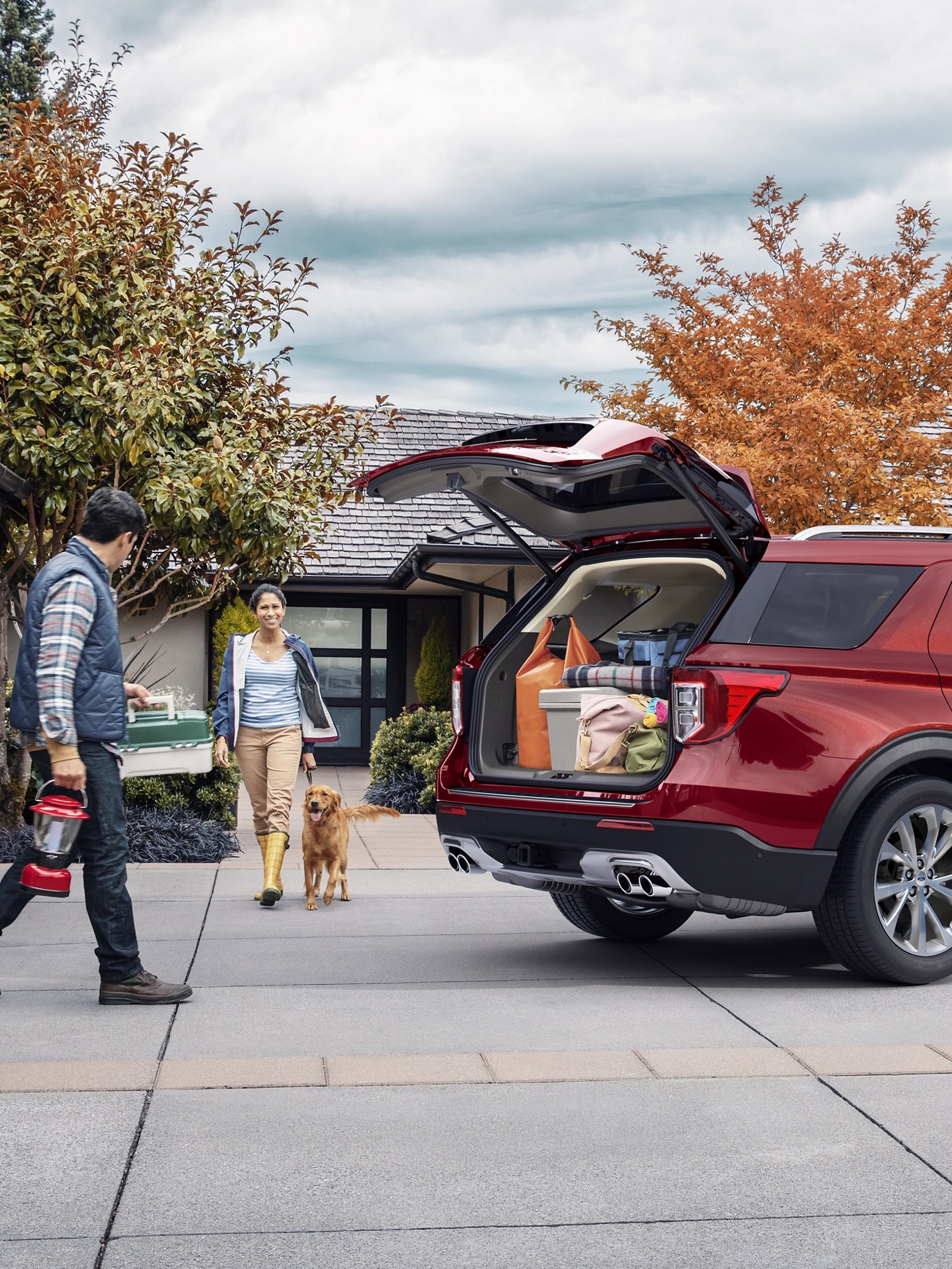 A couple with dog walk towards a Ford SUV