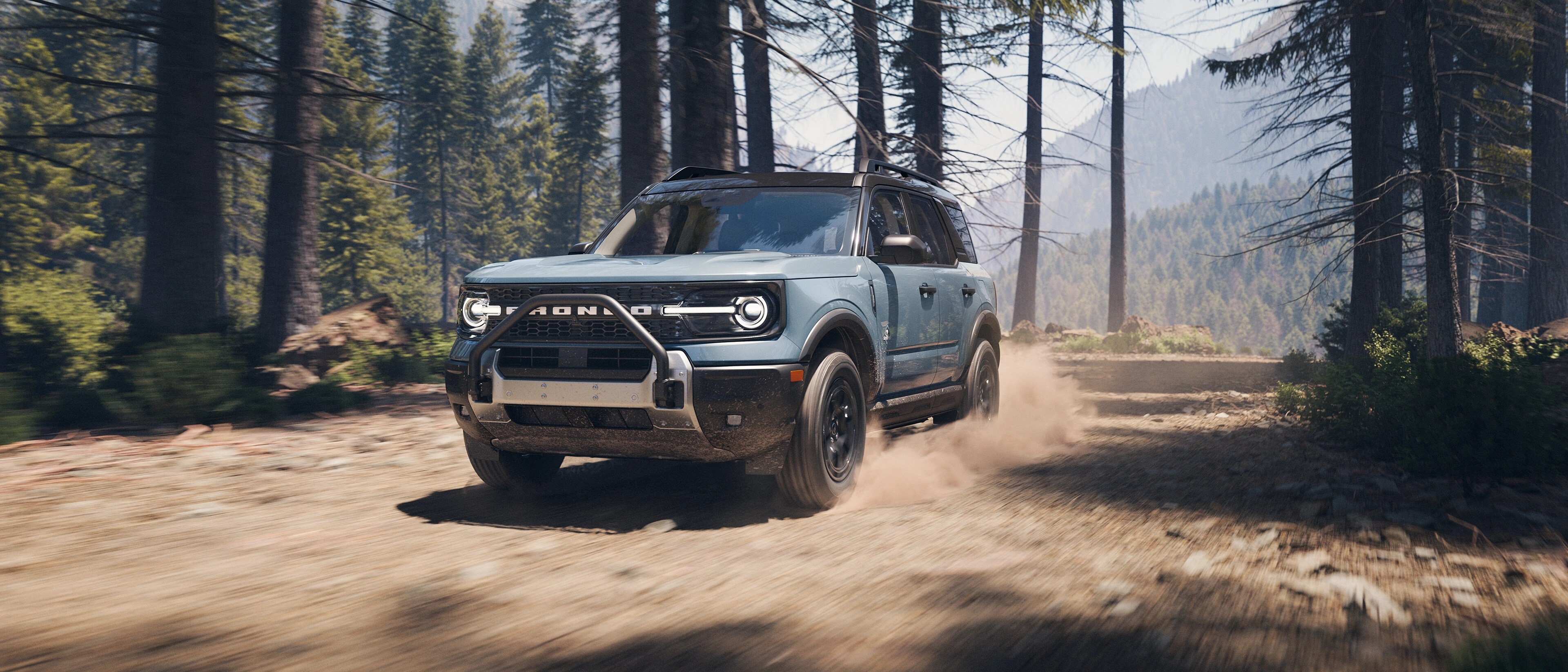2025 Ford Bronco Sport® being driven on a dirt path with trees on either side