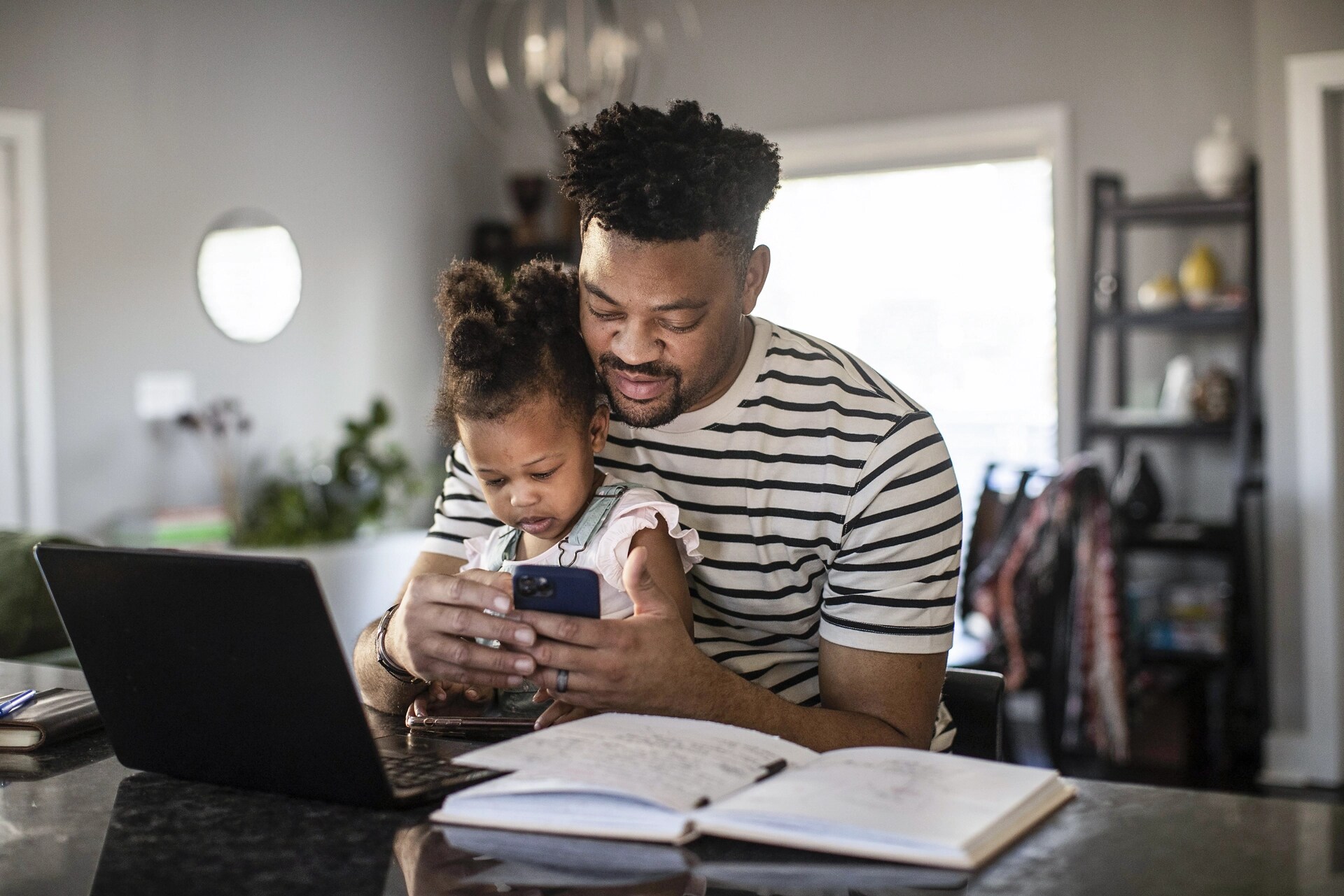 A man holds his child in his lap while interacting with the FordPass app on his phone