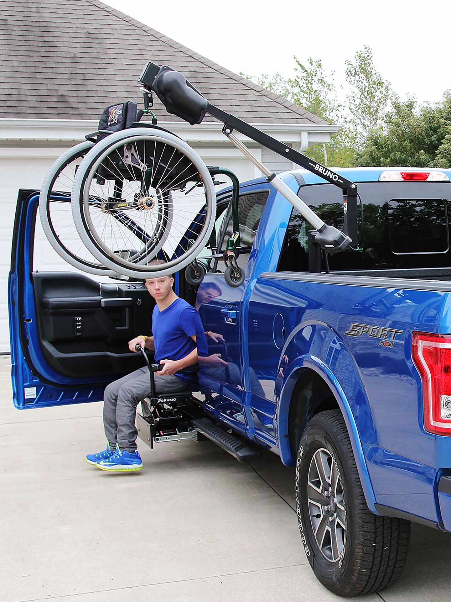 A blue F-150 with a wheelchair hoist in the bed