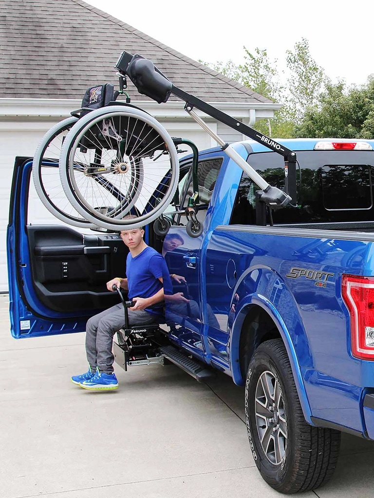 A blue F-150 with a wheelchair hoist in the bed
