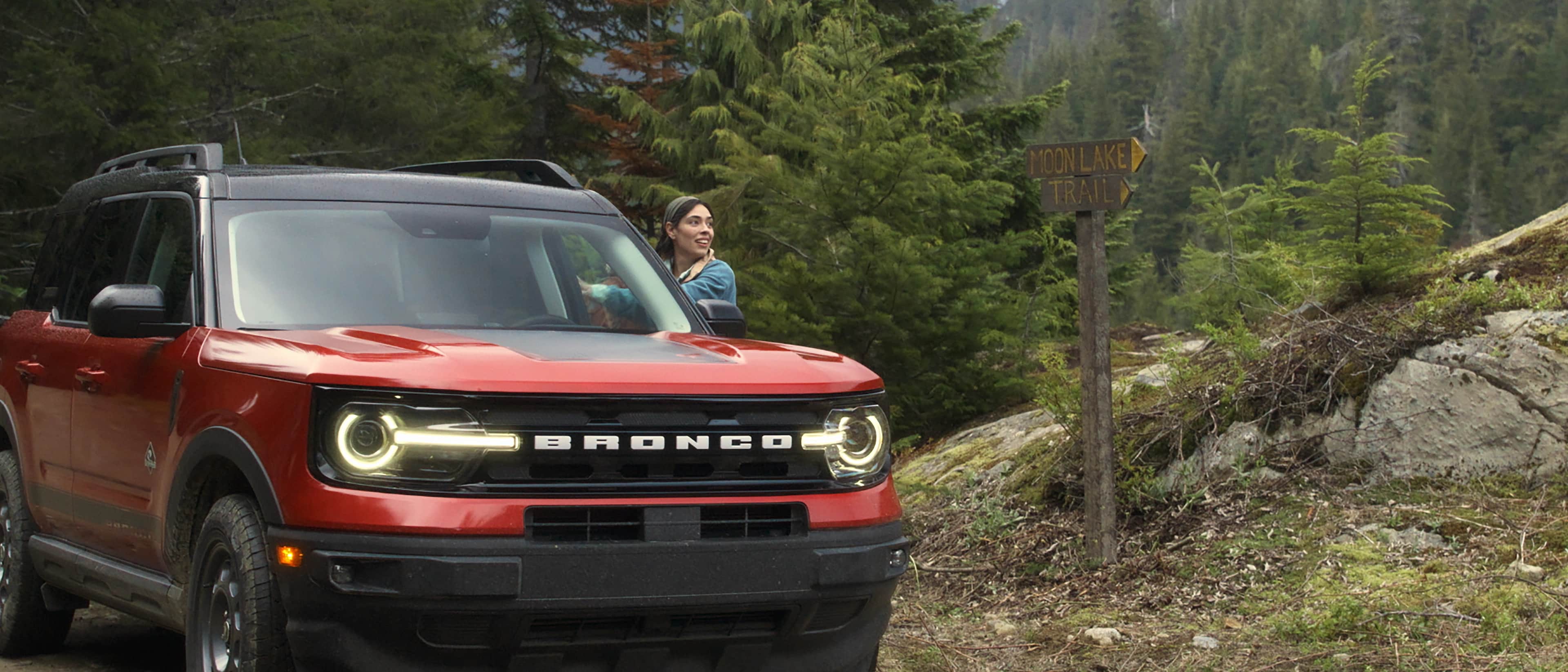 2025 Ford Bronco Sport® parked near trees with a woman standing outside the vehicle