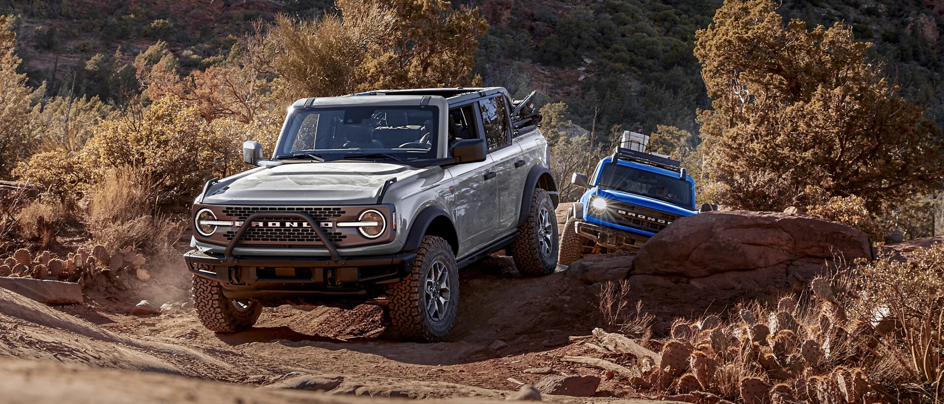 Two 2025 Ford Bronco® SUVs driving on a trail in the high desert