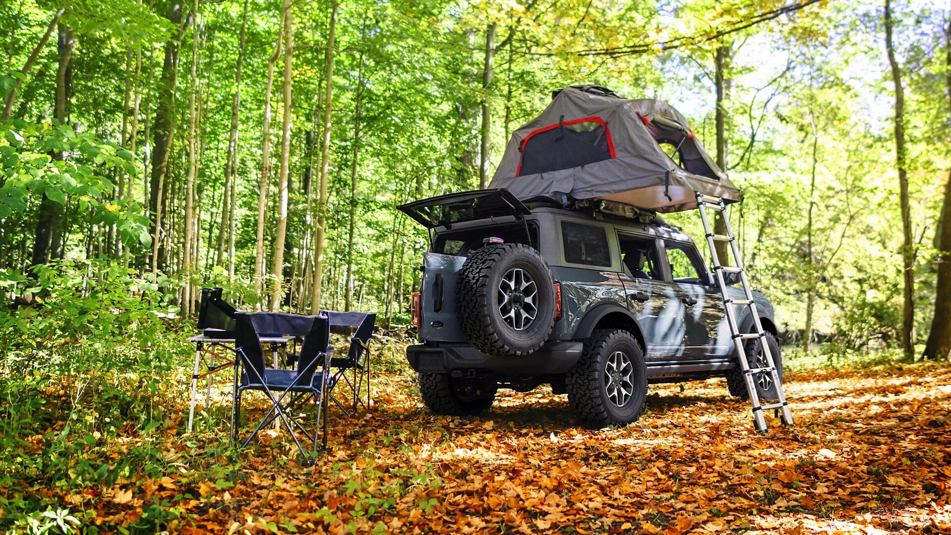 A 2025 Ford Bronco® SUV with a roof tent attached, parked in a forest clearing