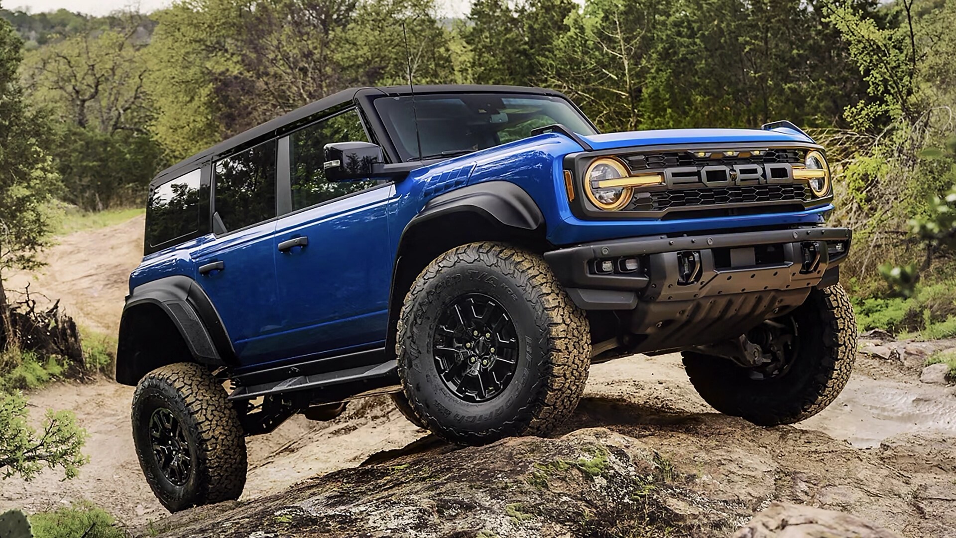 A 2025 Ford Bronco® Raptor® SUV climbing a muddy hill in the forest