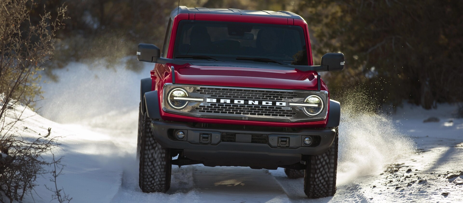 A 2025 Ford Bronco® SUV driving on a snowy trail in the forest