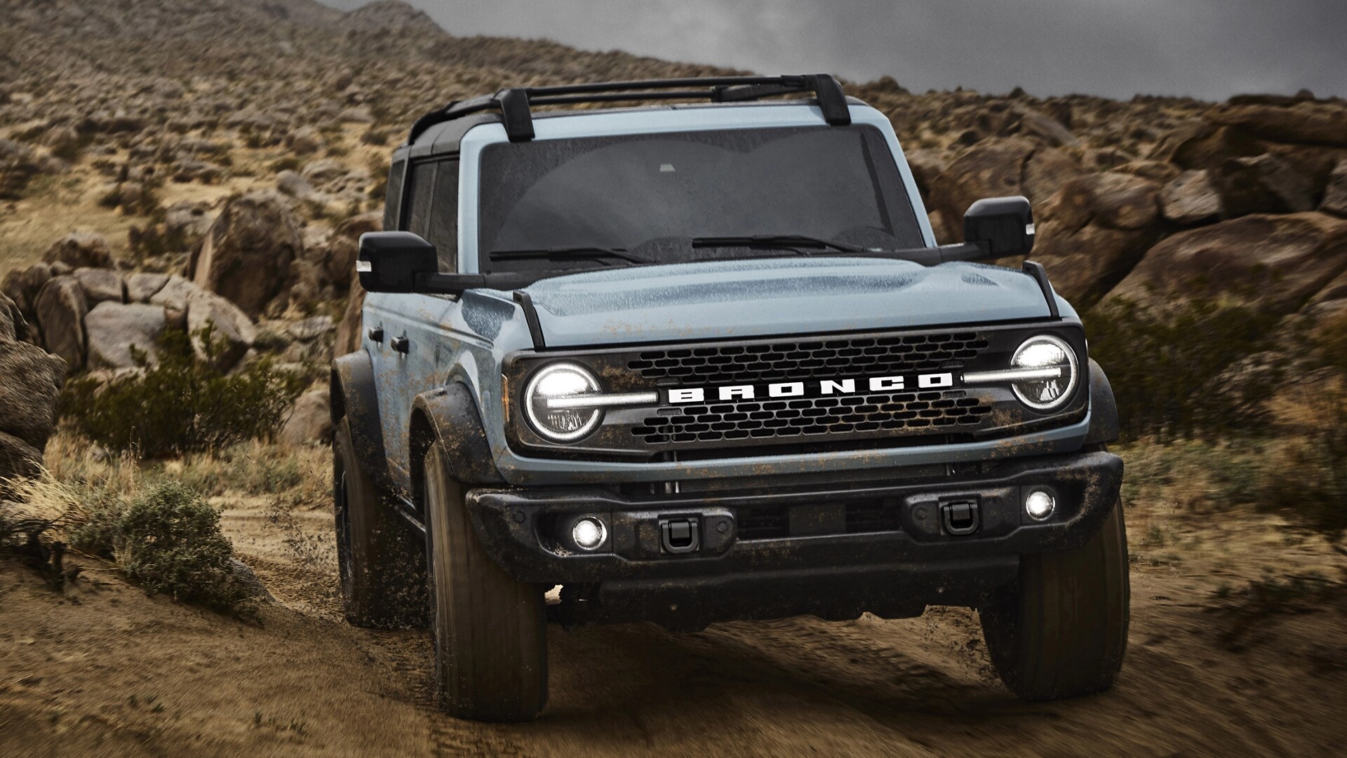 A 2025 Ford Bronco® SUV driving on a dirt trail in the high desert