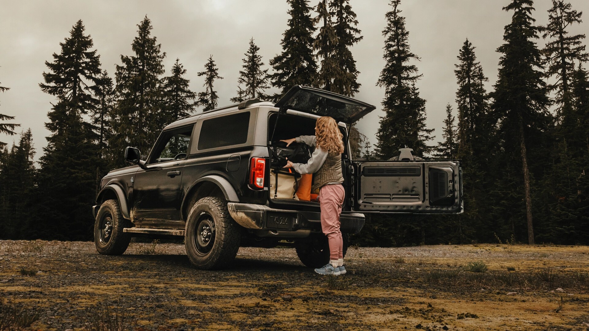 A woman unloading gear from the back of a 2025 Ford Bronco® SUV with the tailgate open