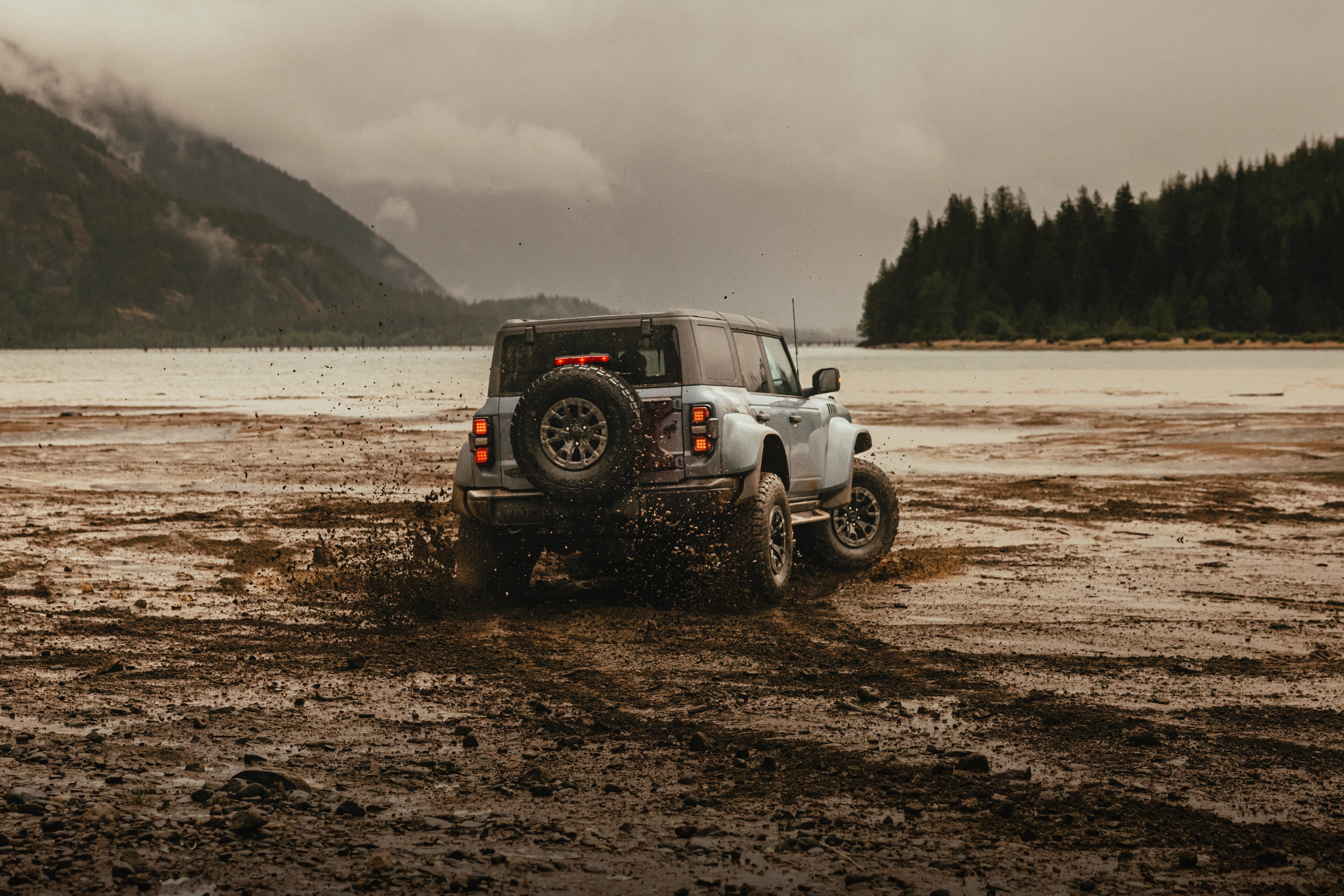 A 2025 Ford Bronco® Raptor® SUV driving on a mud flat in the rain
