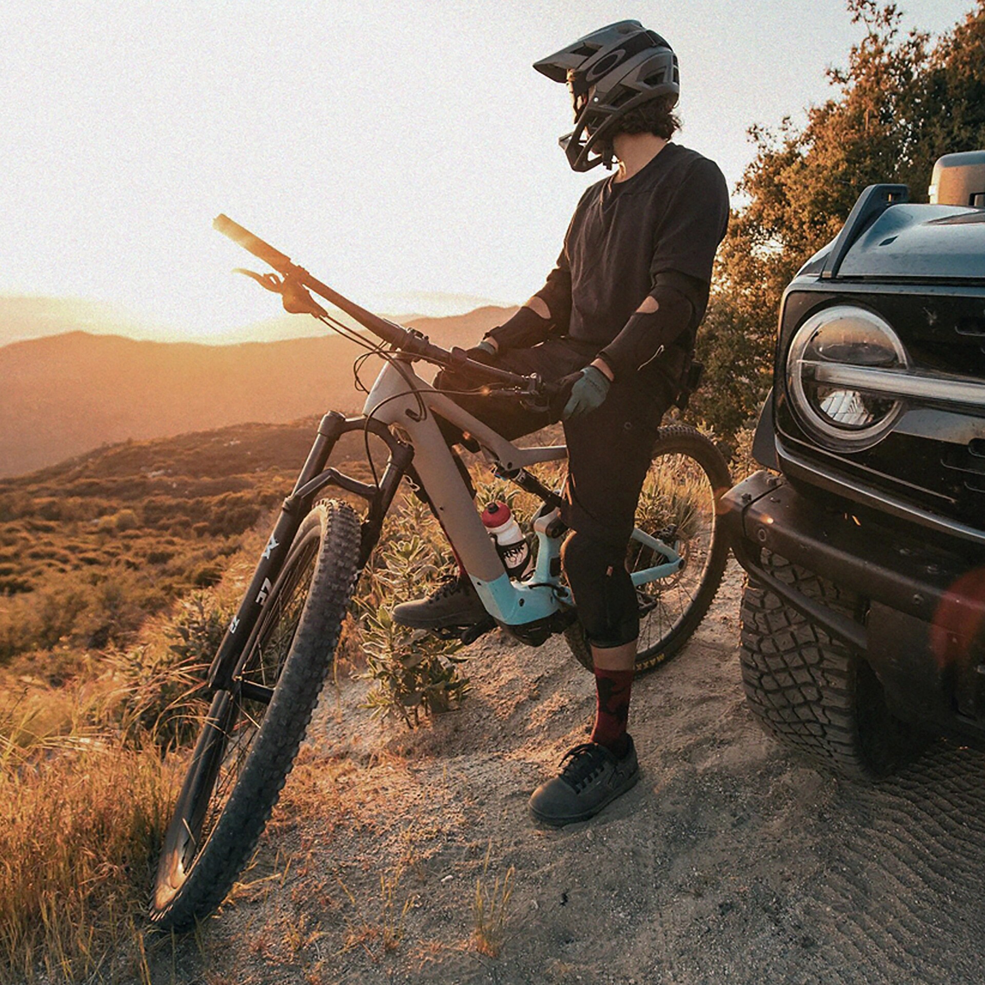 A person sitting astride a dirt bike in protective gear, next to a 2026 Ford Bronco® SUV
