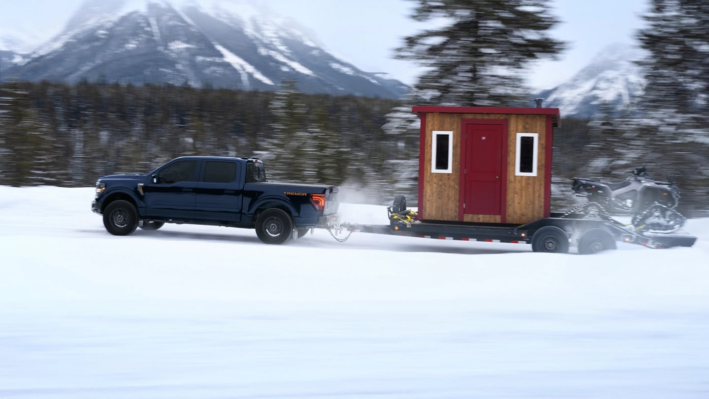 F-150 Tremor towing a hitched ice fishing hut and ATV on a snow-covered trail.