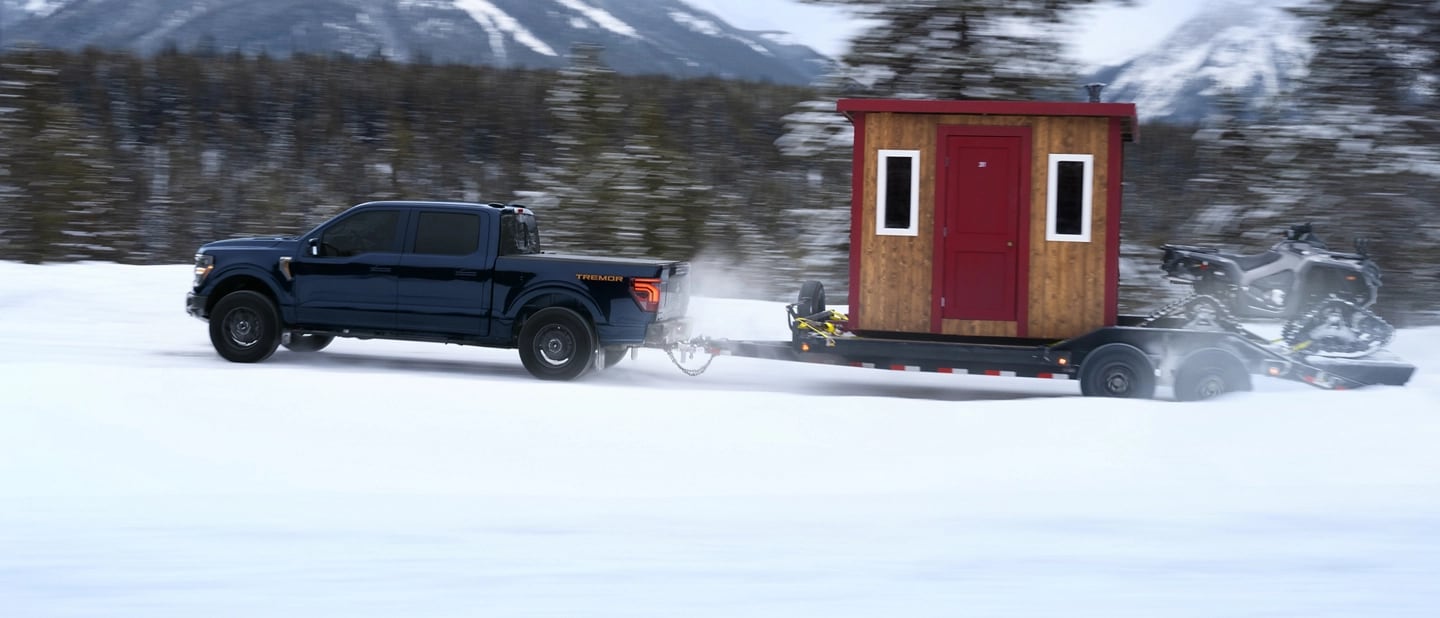 F-150 Tremor towing a hitched ice fishing hut and ATV on a snow-covered trail.
