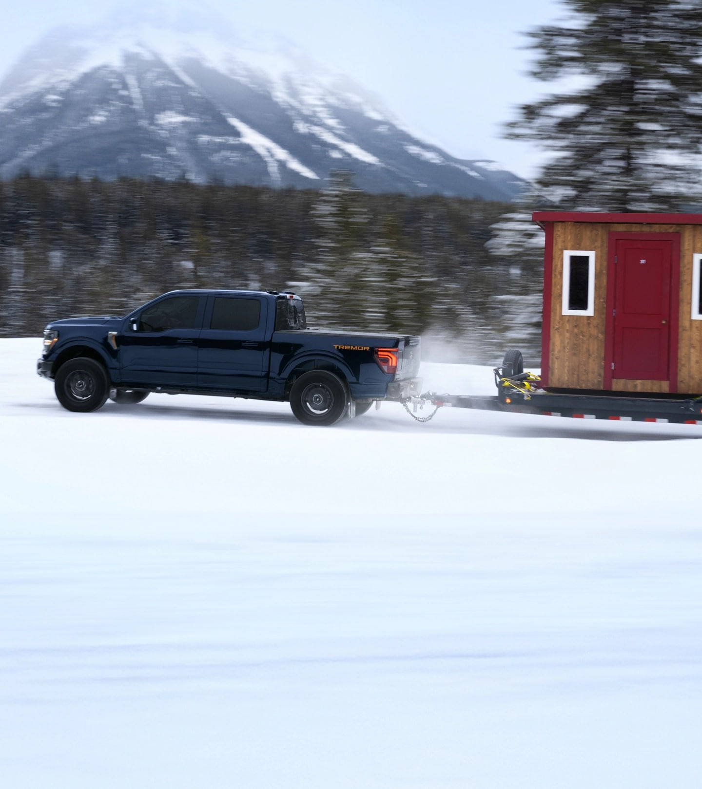 F-150 Tremor towing a hitched ice fishing hut and ATV on a snow-covered trail.