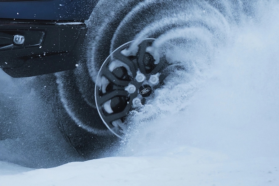 Close-up view of F-150 Tremor tires driving through snow.