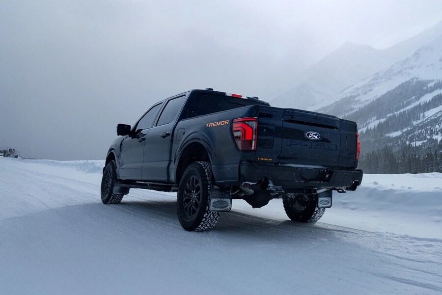 Rear view of an F-150 Tremor driving on a snow-covered mountain road.