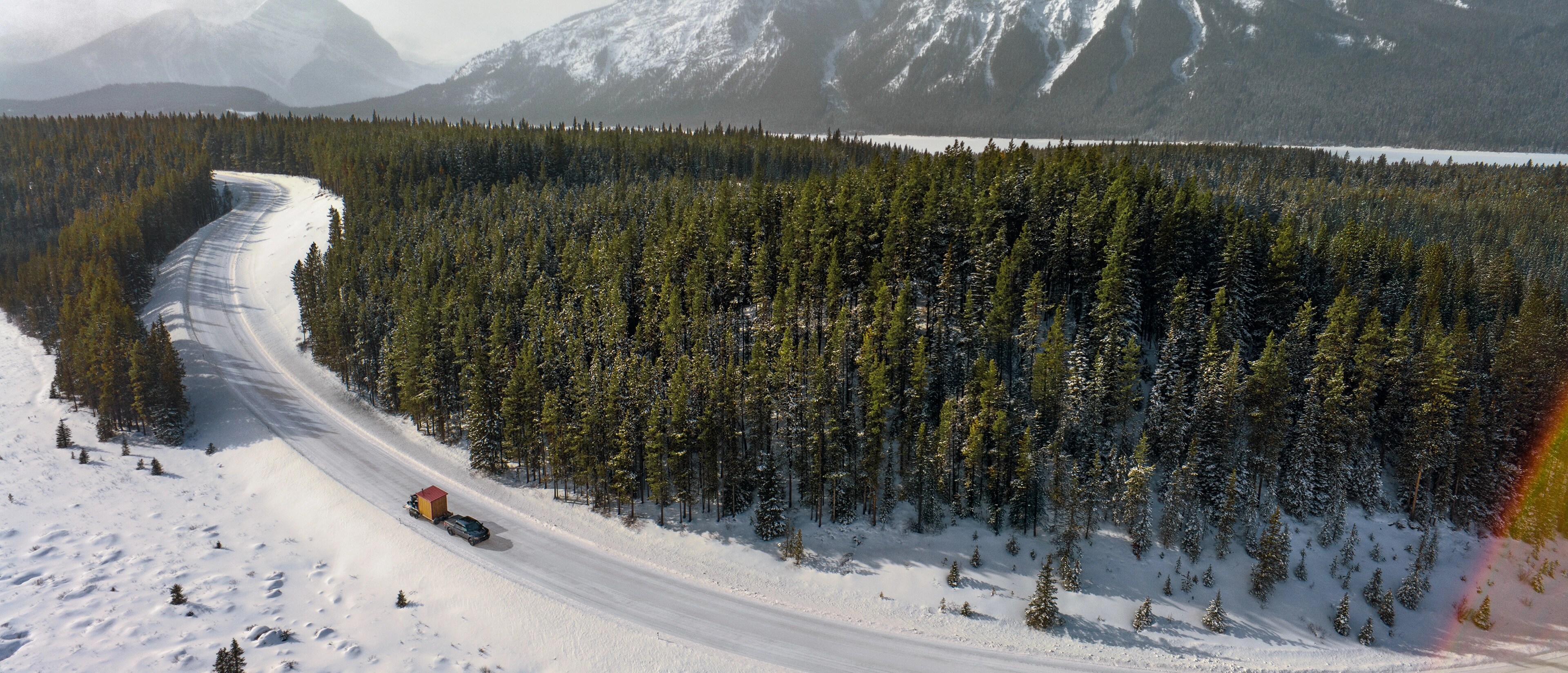 Aerial view of an F-150 Tremor hauling an ice fishing hut and ATV on an icy mountain road.