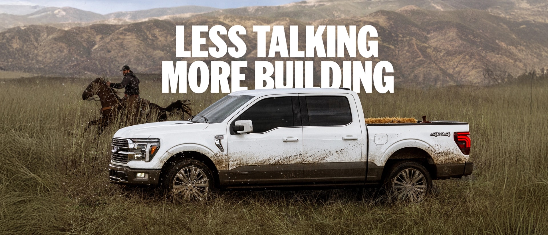 A side profile of a white Ford F-150 driving in a field beside a rider on horseback with a mountain range in the background. "Less talking more building."