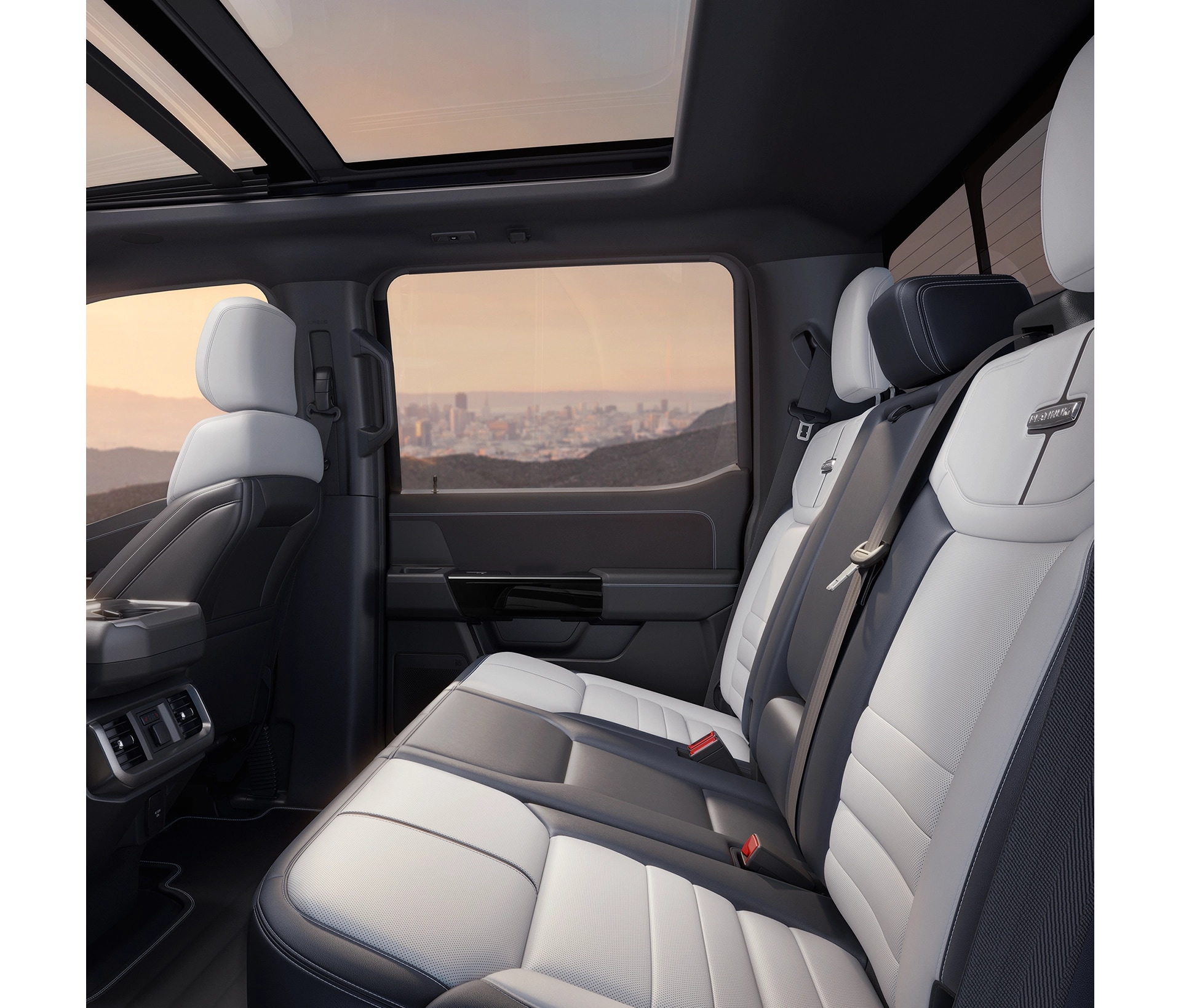 An interior profile view of white rear seats in the F-150 Lightning with a sunset glowing outside side windows. 