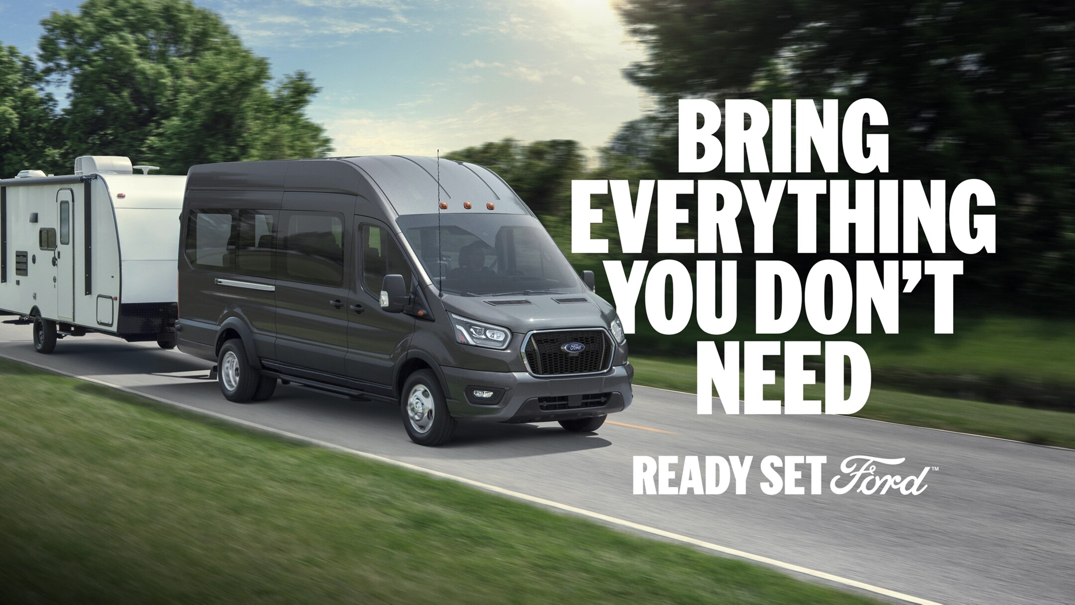 Three-quarter view of a 2025 Ford Transit towing an RV down a scenic road. White text “Bring Everything You Don’t Need” appears to the right of the Transit. In the lower right-hand corner appears white text “Ready Set Ford.”
