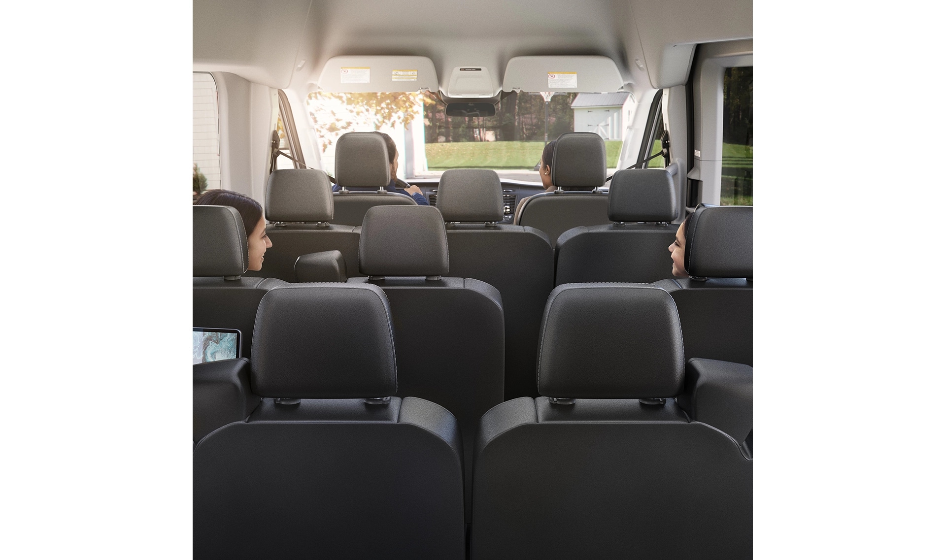 A rear view of the Ford Transit interior with all seats upright and four passengers inside. 