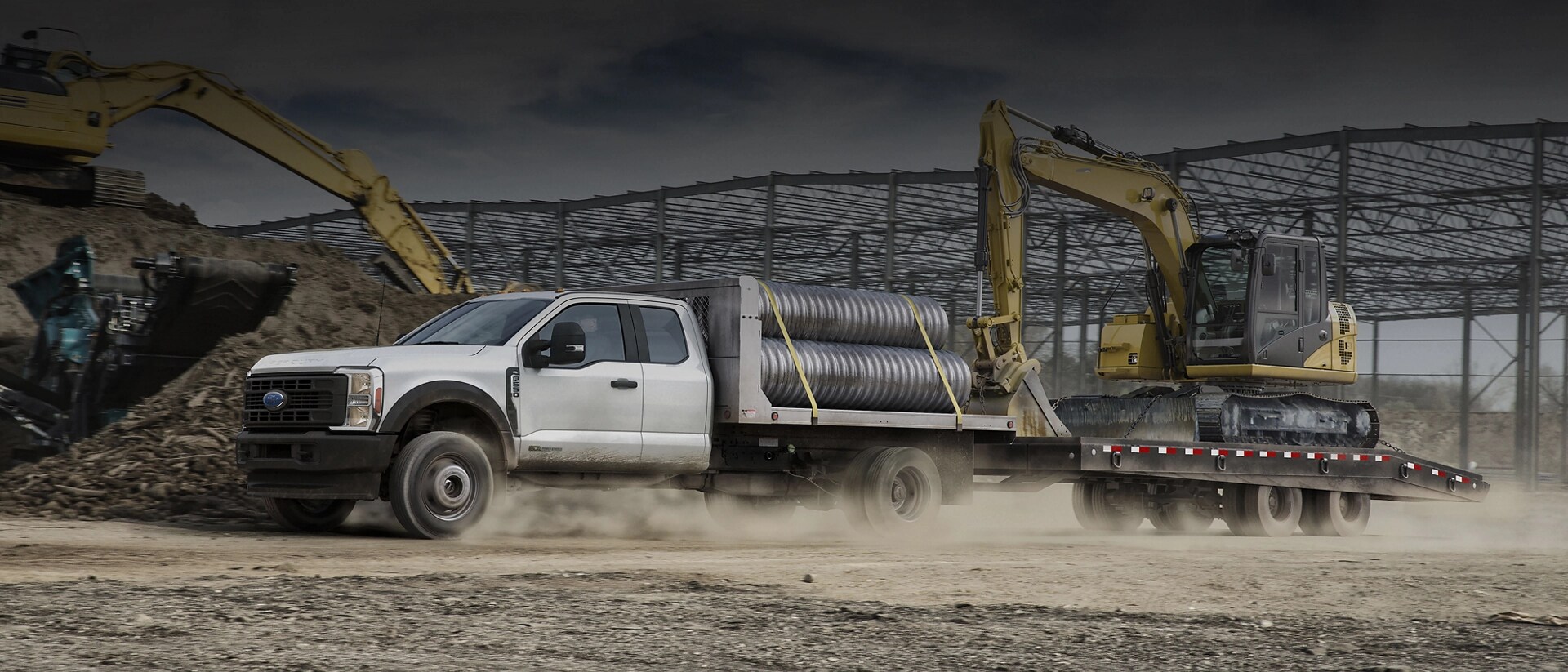 2026 Ford Super Duty® Chassis Cab loaded with pipes and pulling a trailer with a backhoe