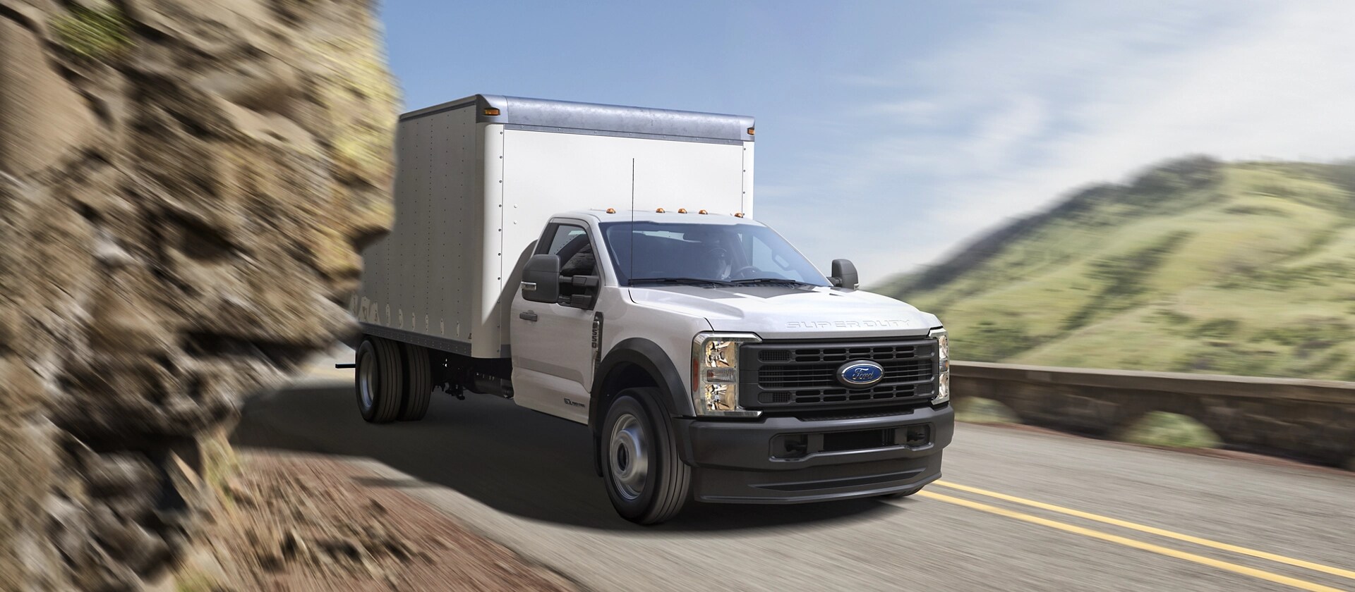 A 2026 Ford Super Duty® Chassis Cab with a box being driven through a tight mountain curve