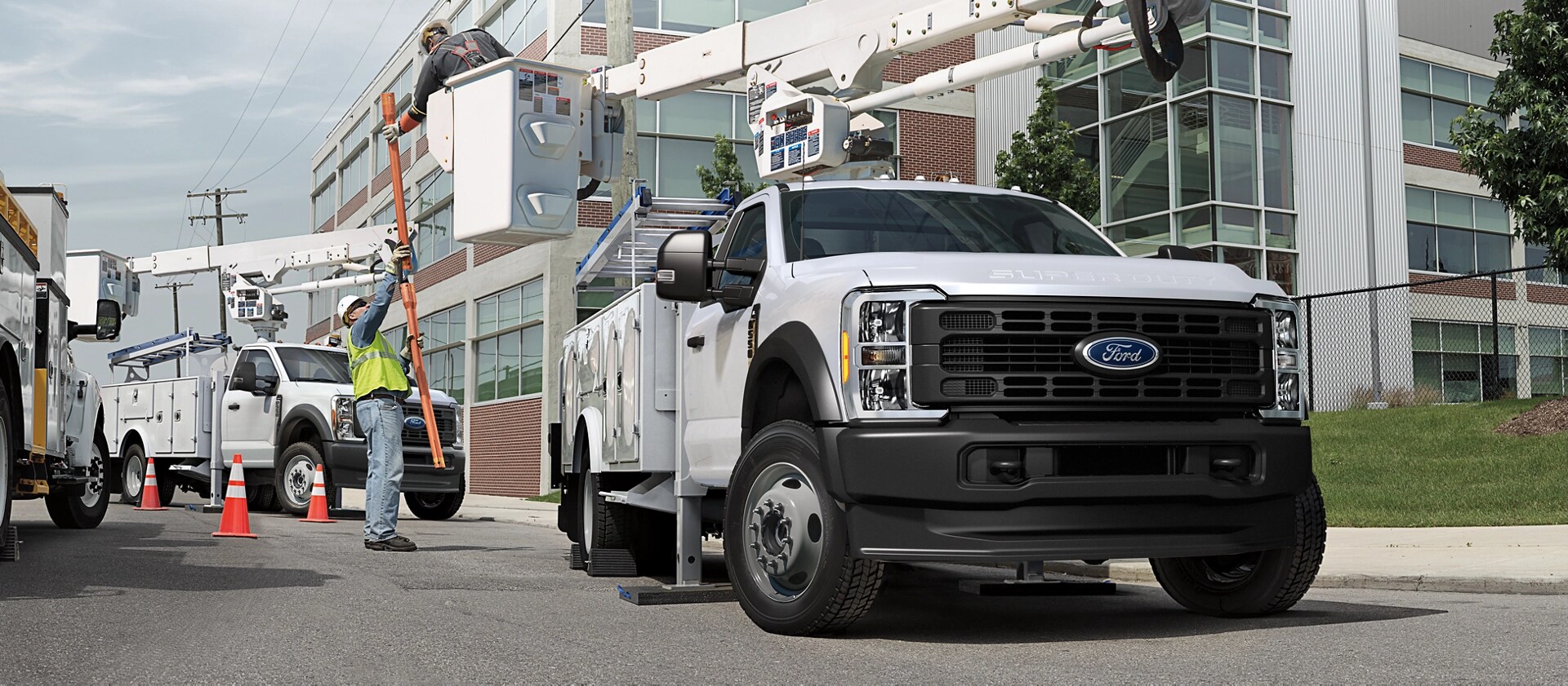 Two workers using the boom extension on a 2026 Ford Super Duty® Chassis Cab to fix an electric poll