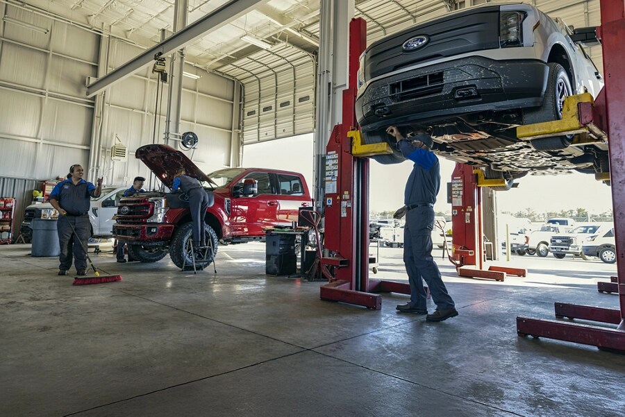 Mechanics working on vehicles in a repair shop.