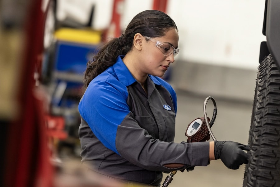 A Ford Service Technician works on a tire on a lifted vehicle.