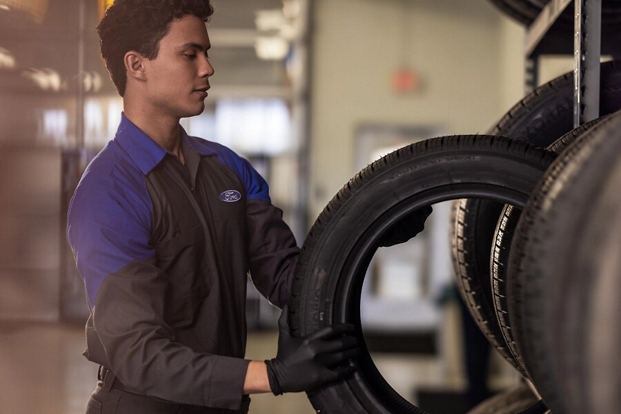 Ford technician pulls a tire from a shelf.