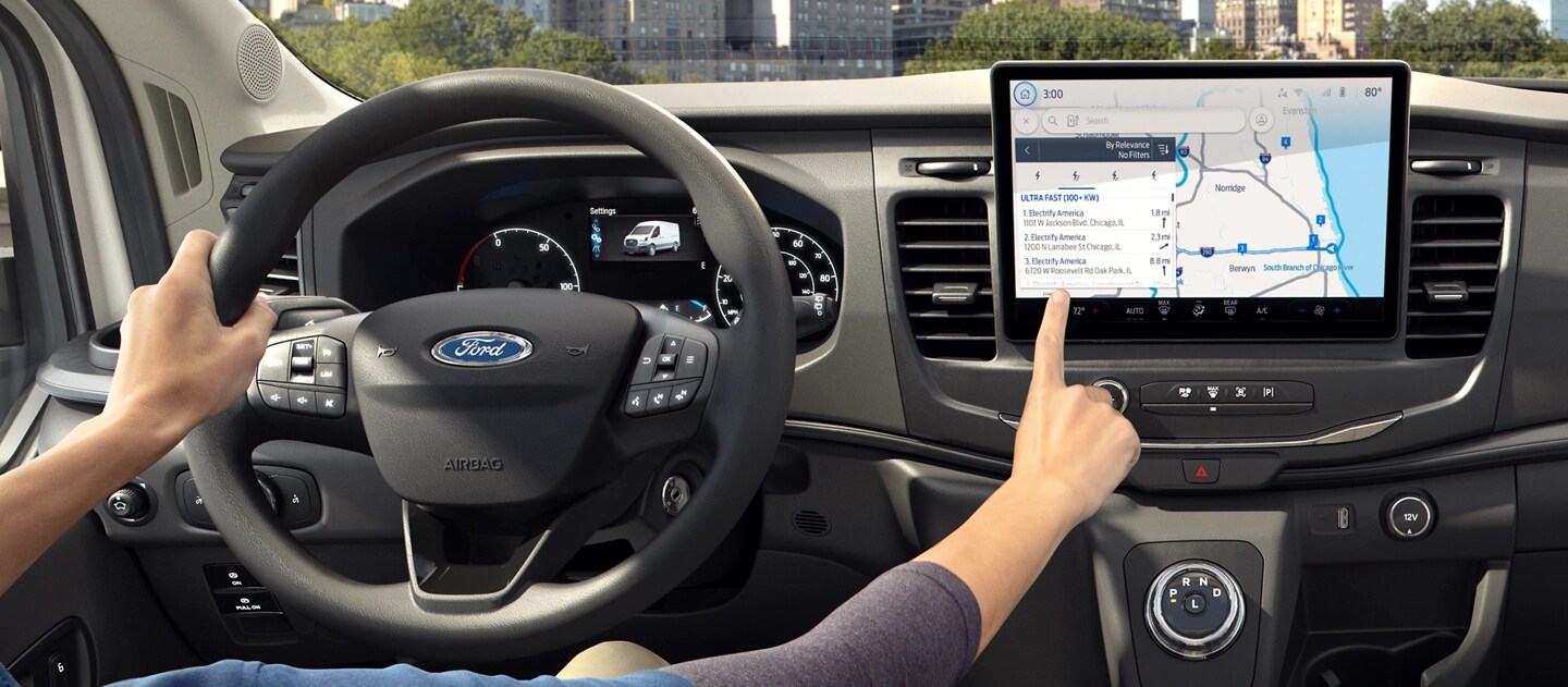 The interior of a 2025 Ford E-Transit™ showing a person touching the computer display