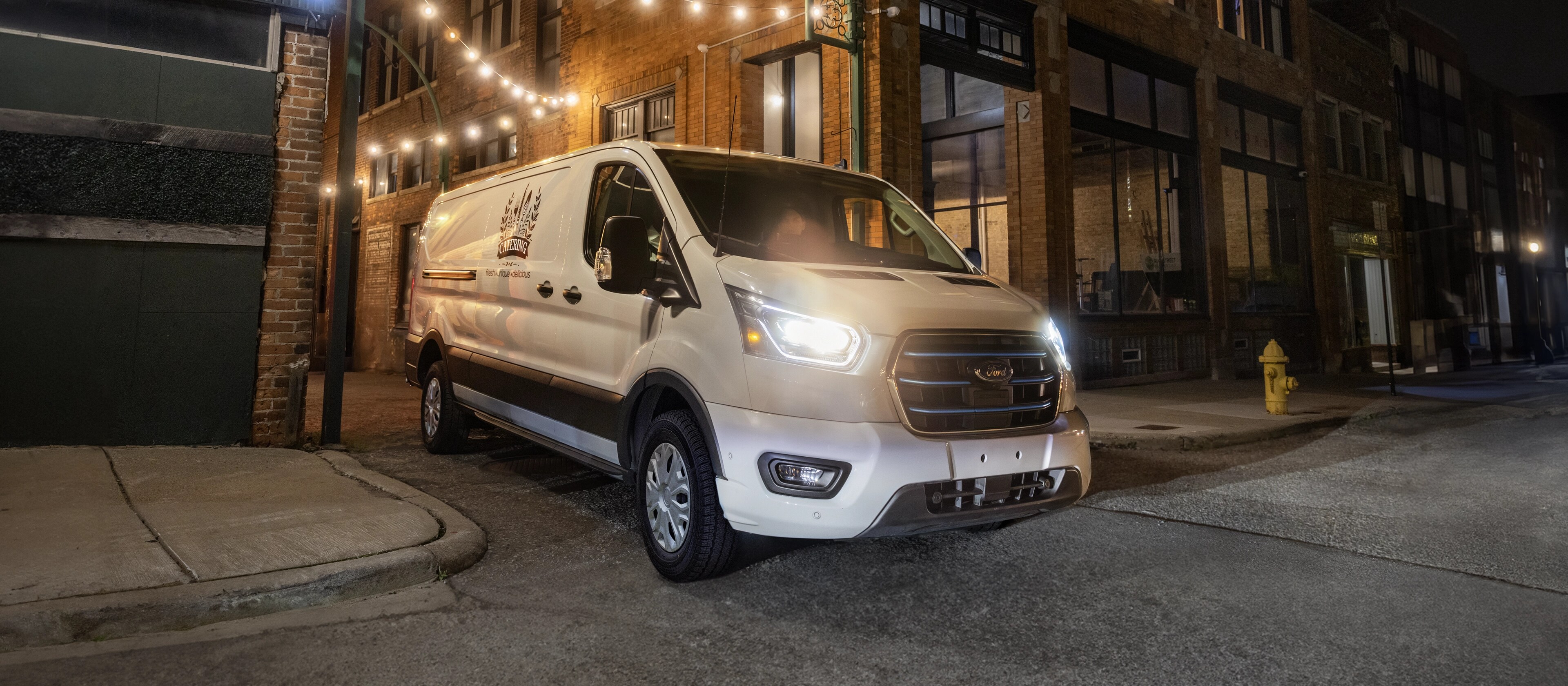 A white 2025 Ford E-Transit™ van backing into a delivery spot
