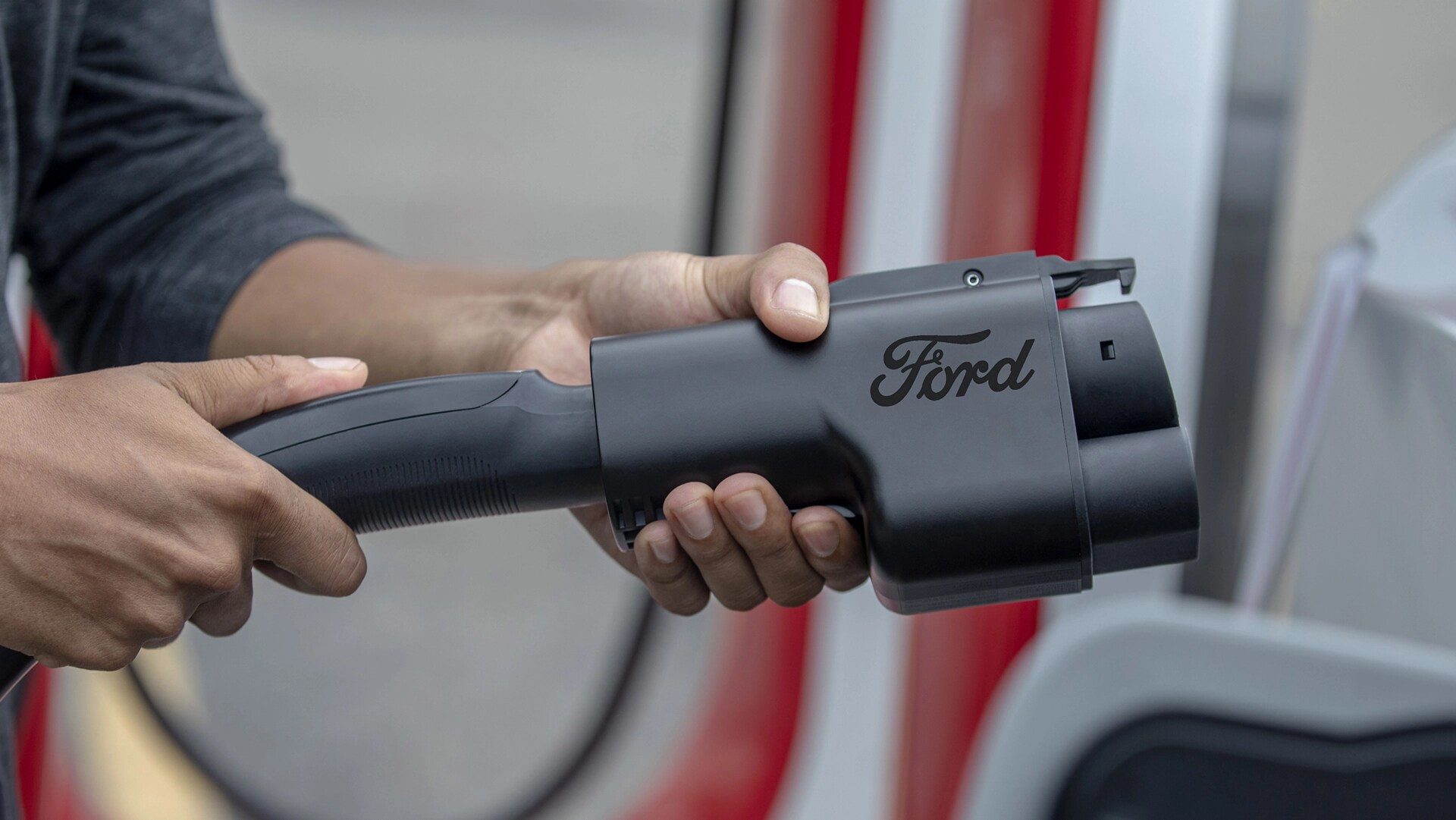 Person using the NACS charging adapter for a Tesla Supercharger